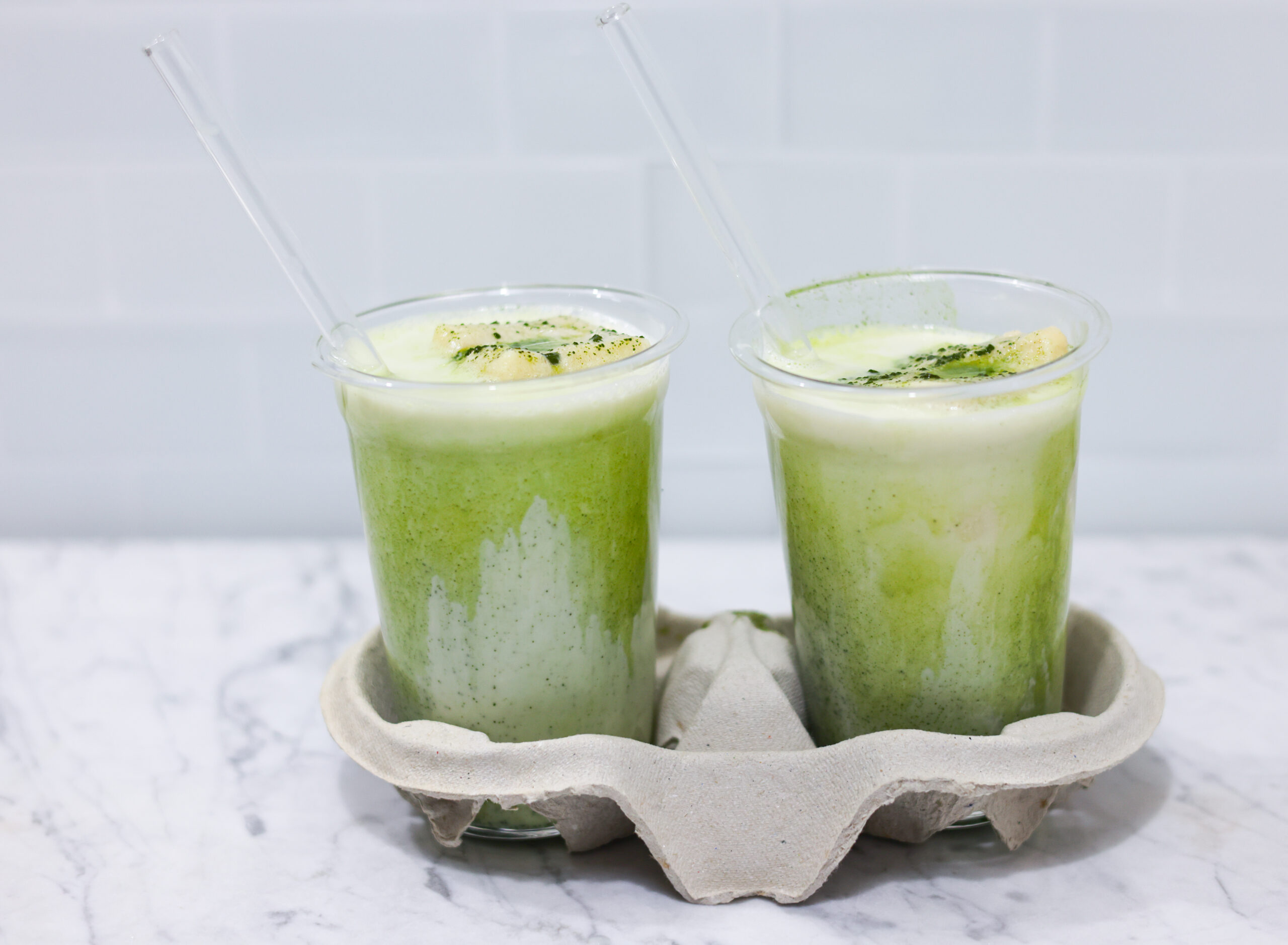 In this picture you can see two Iced Matcha Latte in cold cup glasses from the company within mood on Carrara marble.
In the background are white metro tiles