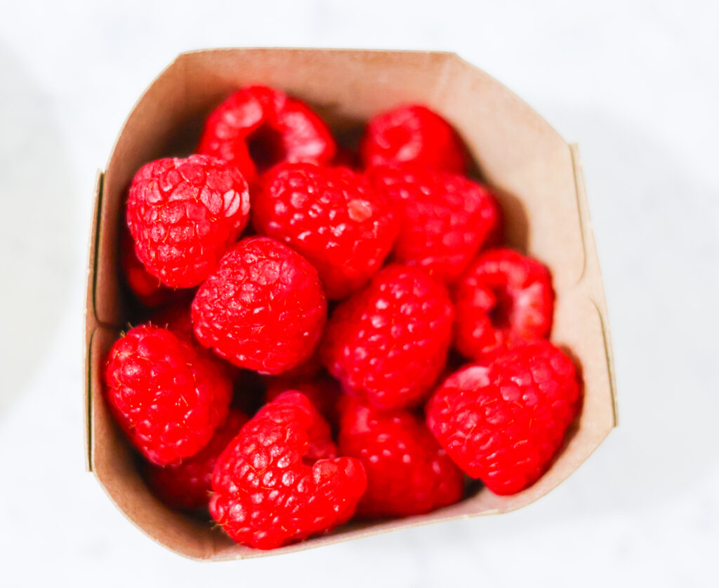 In this photo, you can see an açai bowl ingredients such as raspberries