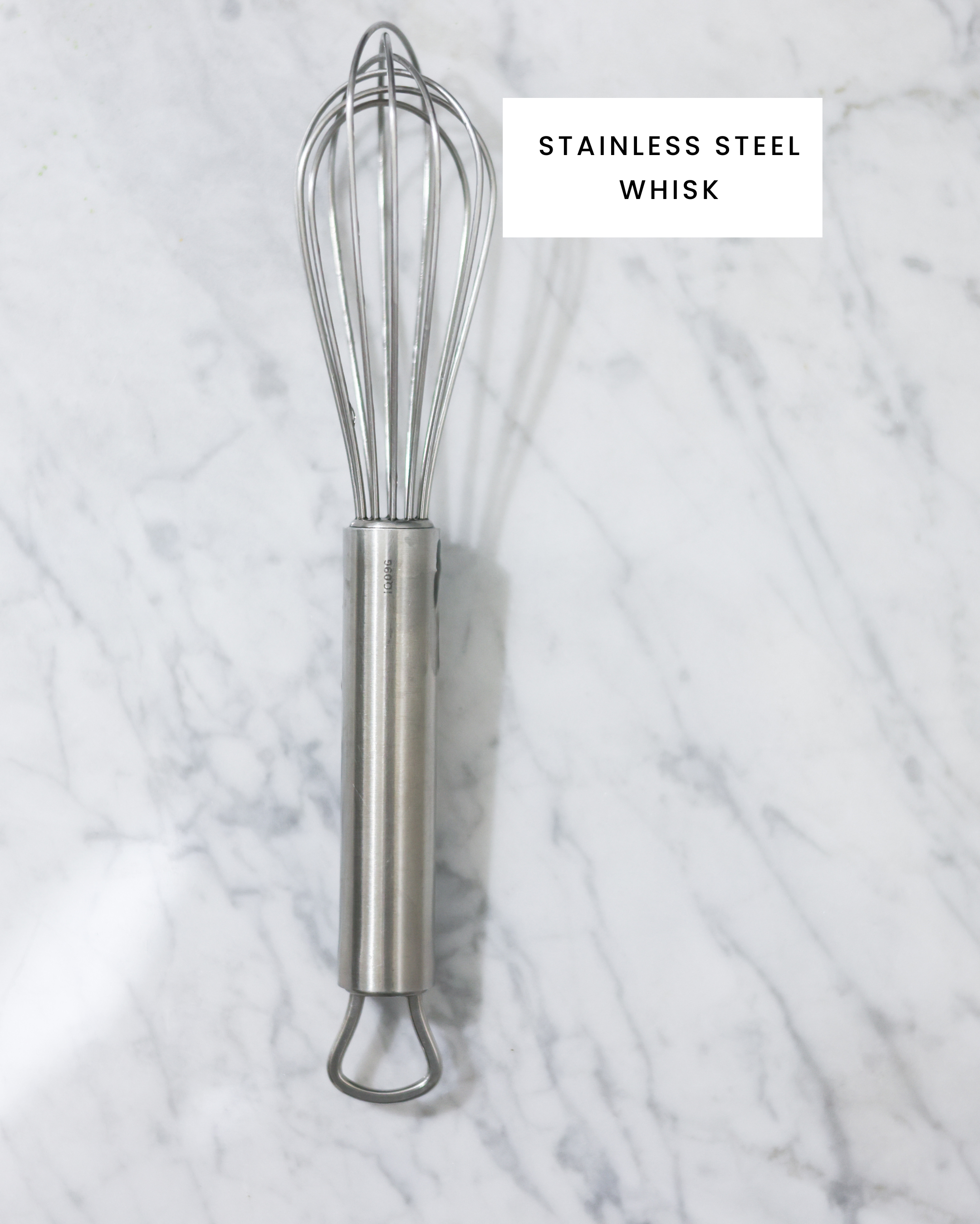 The picture shows a stainless steel whisk on carrara marbl