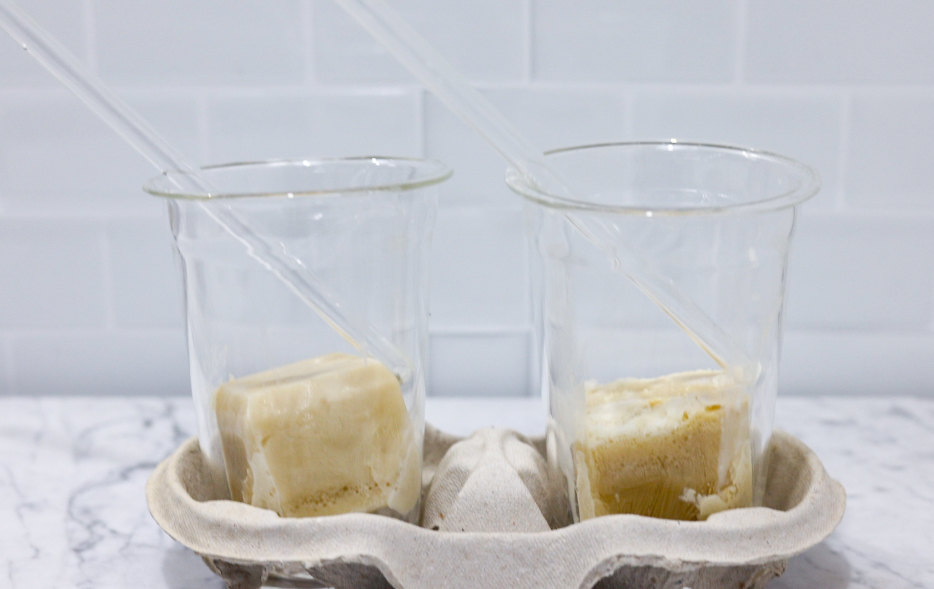 In this picture you can see two cold cup glasses filled with homemade oat milk creamer ice cubes.
The cups are from the company within mood.
Underneath you can see carrara marble.
In the background are white metro tiles