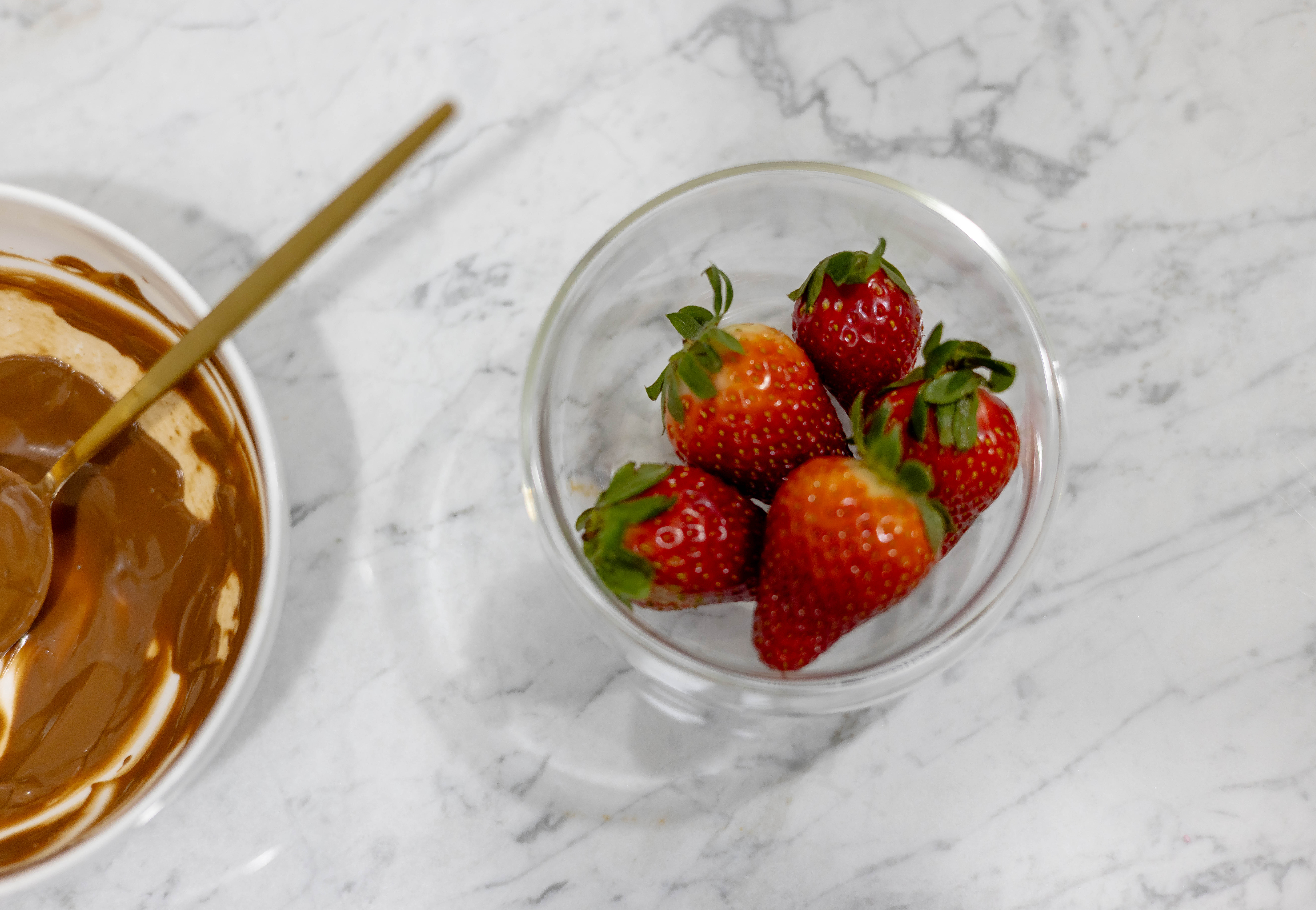 In this picture you can see a fine bone china jar filled with vegan warm chocolate. 

Next to the chocolate jar is one small Double-walled bowl with red organic juicy strawberries. The whole setting is positioned on a white Carrara marble desk.
