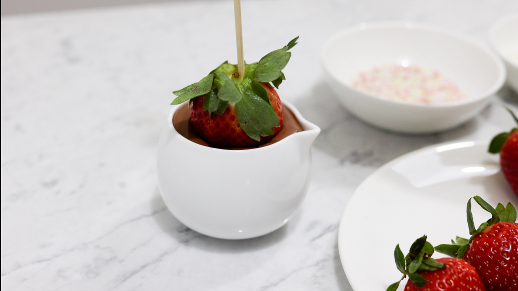 In this picture you can see strawberries being dipped in to vegan chocolate sauce