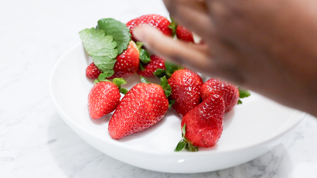 In this picture you can see, a hand tapping the strawberries dry. The strawberries a plated on a fine bone china porcelain plate. 

The whole setting is positioned on a white Carrara marble desk.
