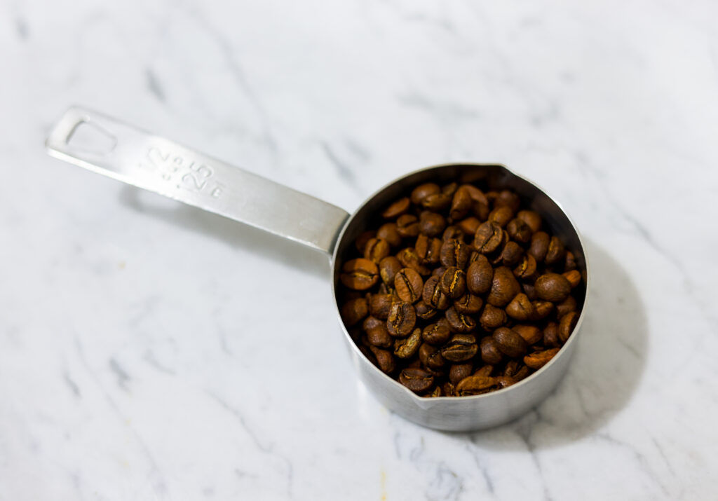 In this picture you can see the barn coffee beans spread on the carrara marble. All objects are placed on white carrara marble and in the back are white metro tiles.