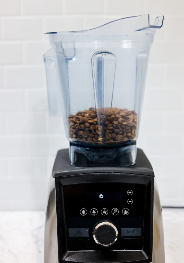 In this picture you can see the barn coffee beans in a vitamix container. All objects are placed on white carrara marble and in the back are white metro tiles.