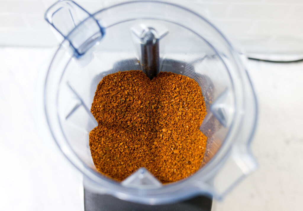 In this picture you can see the barn coffee beans grounded coarsely in a Vitamix container. All objects are placed on white carrara marble and in the back are white metro tiles.