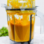 In this photo you can see a vitamix container with a puréed Vitamix Thai Pumpkin Soup in it.