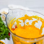 In this photo you can see a vitamix container with a puréed Vitamix Thai Pumpkin Soup in it.