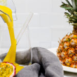 In this picture you can see the Mango Pineapple Smoothie poured into a crystal glass. In the back is a flight pineapple